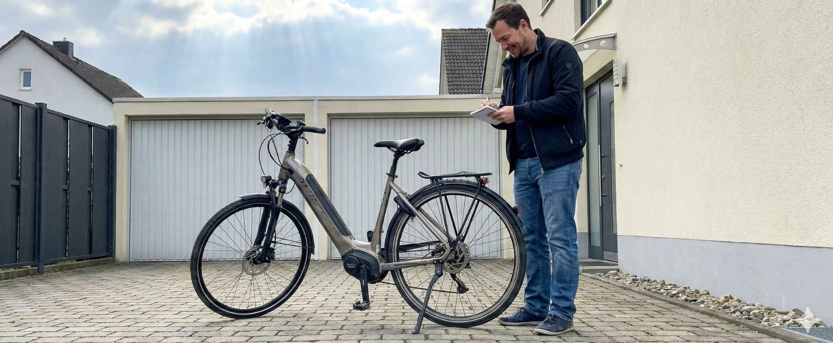 Mann rechnet Restwert aus. Neben ihm steht sein E-Bike.