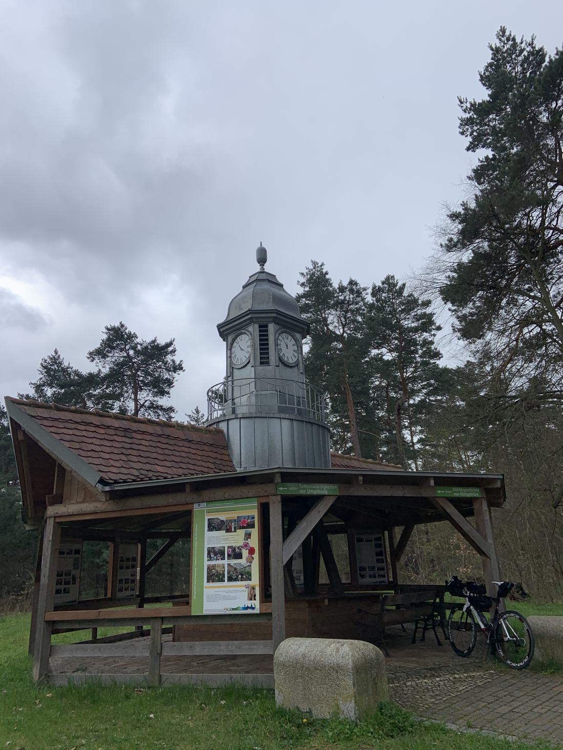 Kurze Rast an einem Uhrturm mit Infotafel zu den Sehenswürdigkeiten der Umgebung